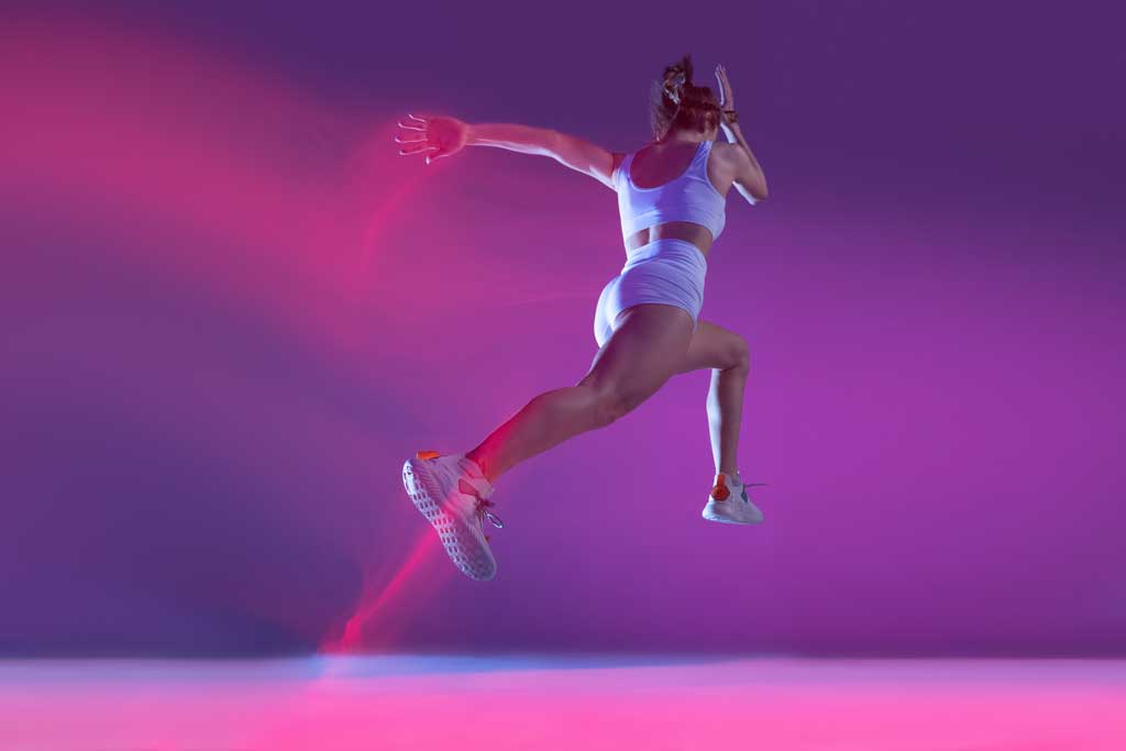 dynamisches-portraet-einer-jungen-sportlichen-frau-die-isoliert-ueber-violettem-hintergrund-in-neon-mit-gemischten-lichtern-laeuft-sm